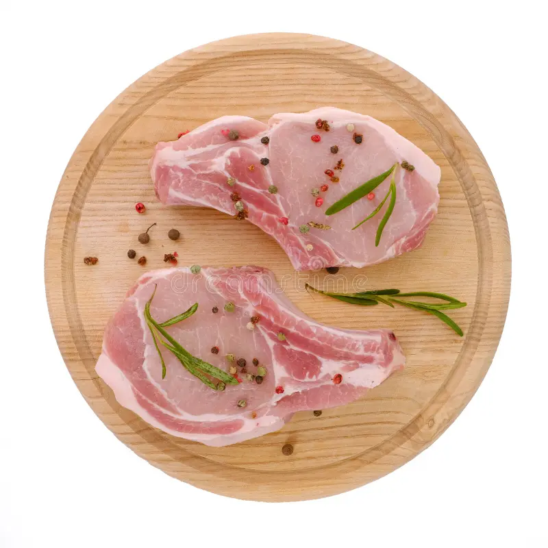 cortes o chuletas de cerdo crudos en una tabla corte redonda con especias aisladas fondo blanco ver desde arriba paro plano 253151800